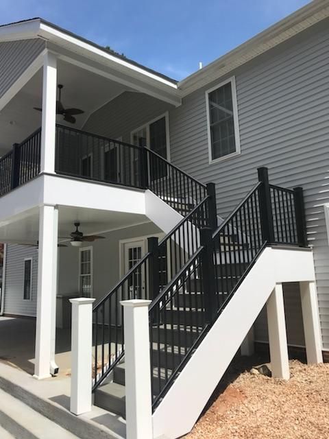 Exterior staircase and balcony on a gray house with black railings and white support posts