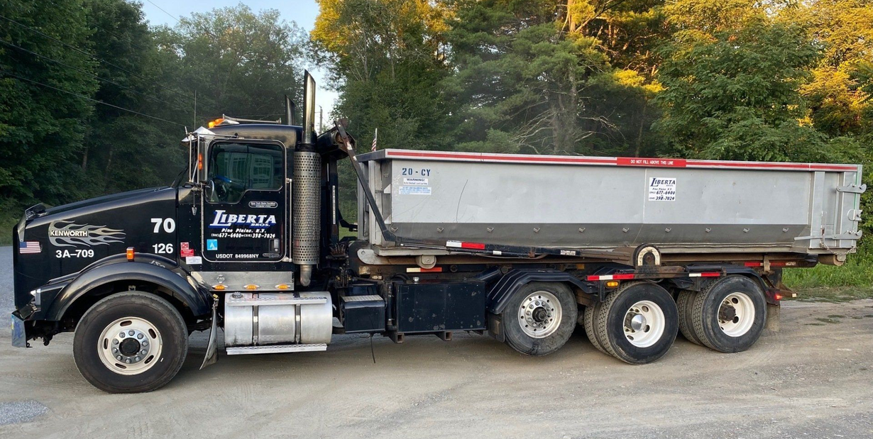 Blue and silver dump truck with a red cargo bed parked outside.