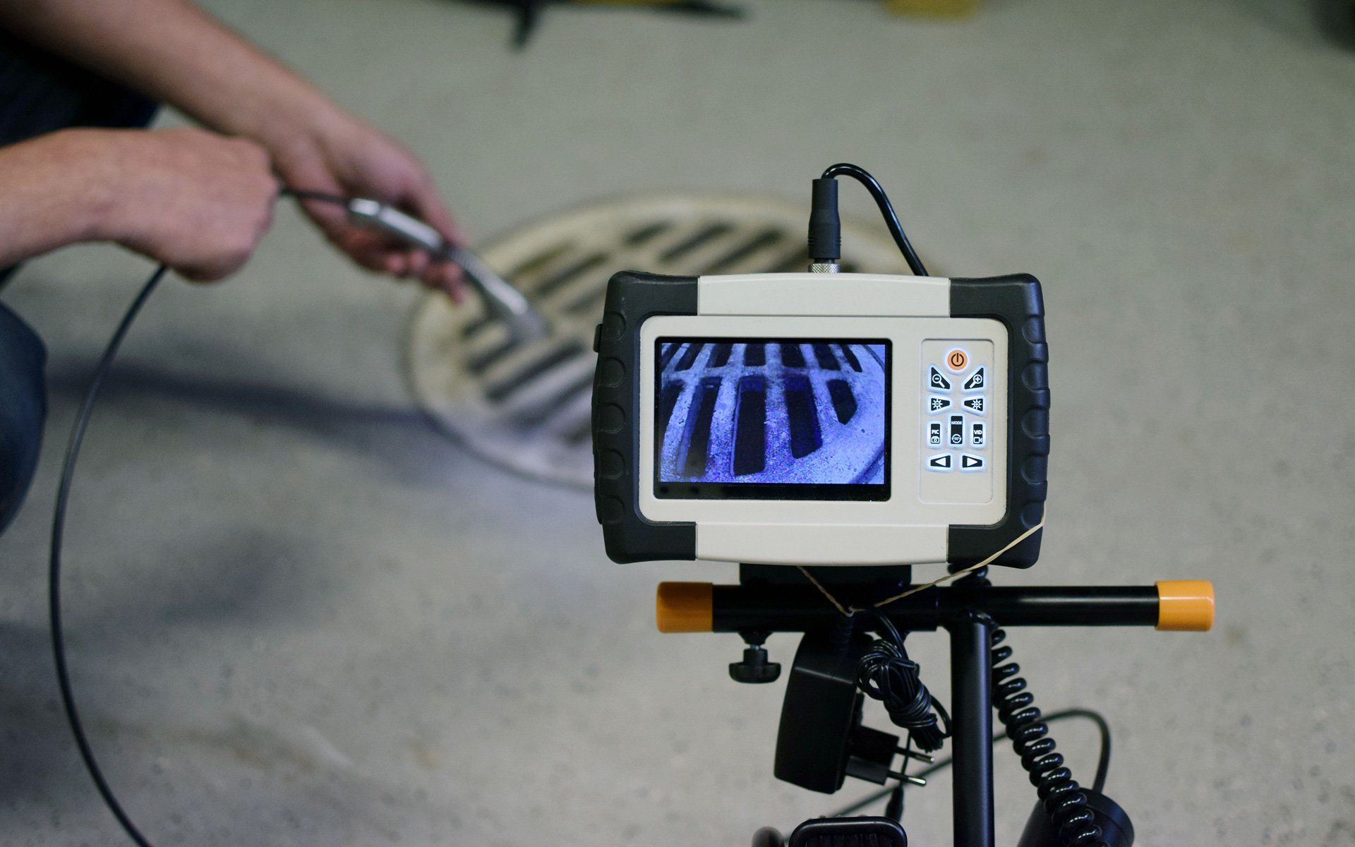 A man is using a camera to look at a manhole cover.