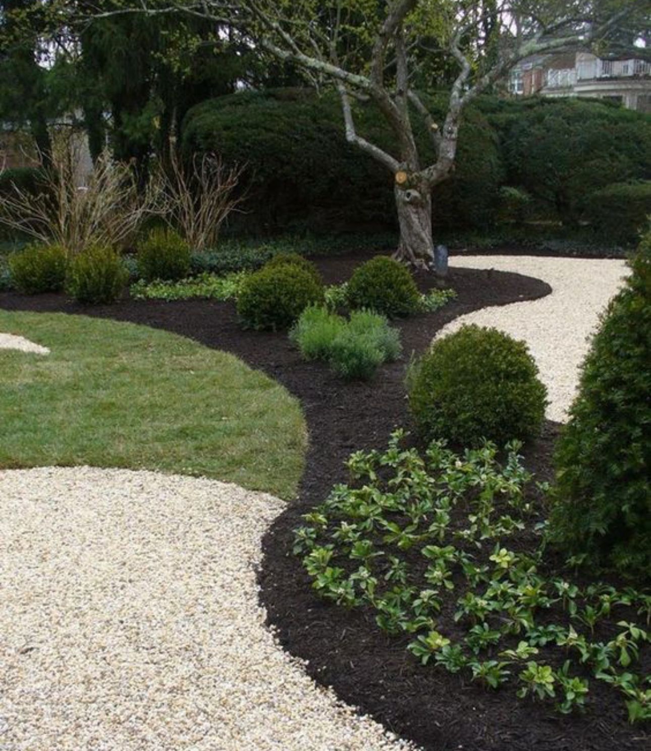 Stump grinder attached to a skid steer removing a tree stump on a grassy lawn.