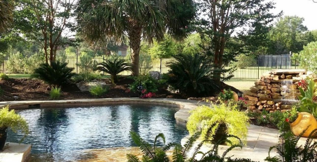 Swimming pool with lush landscaping and waterfall feature.