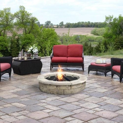 Patio with fire pit, red cushioned seating, and stone pavers in a rural setting.
