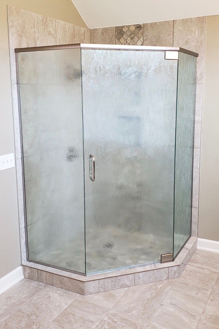 Corner glass shower enclosure with a chrome frame in a tiled bathroom
