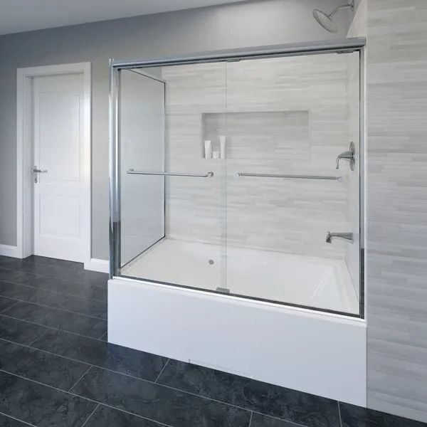 A bathtub with a sliding glass door and chrome hardware, set against light-toned tiled walls and dark gray floor tiles.