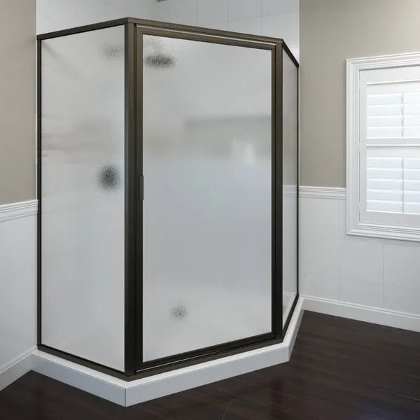 A neo-angle shower enclosure with dark bronze frames and frosted glass panels in a bathroom with white wall paneling.