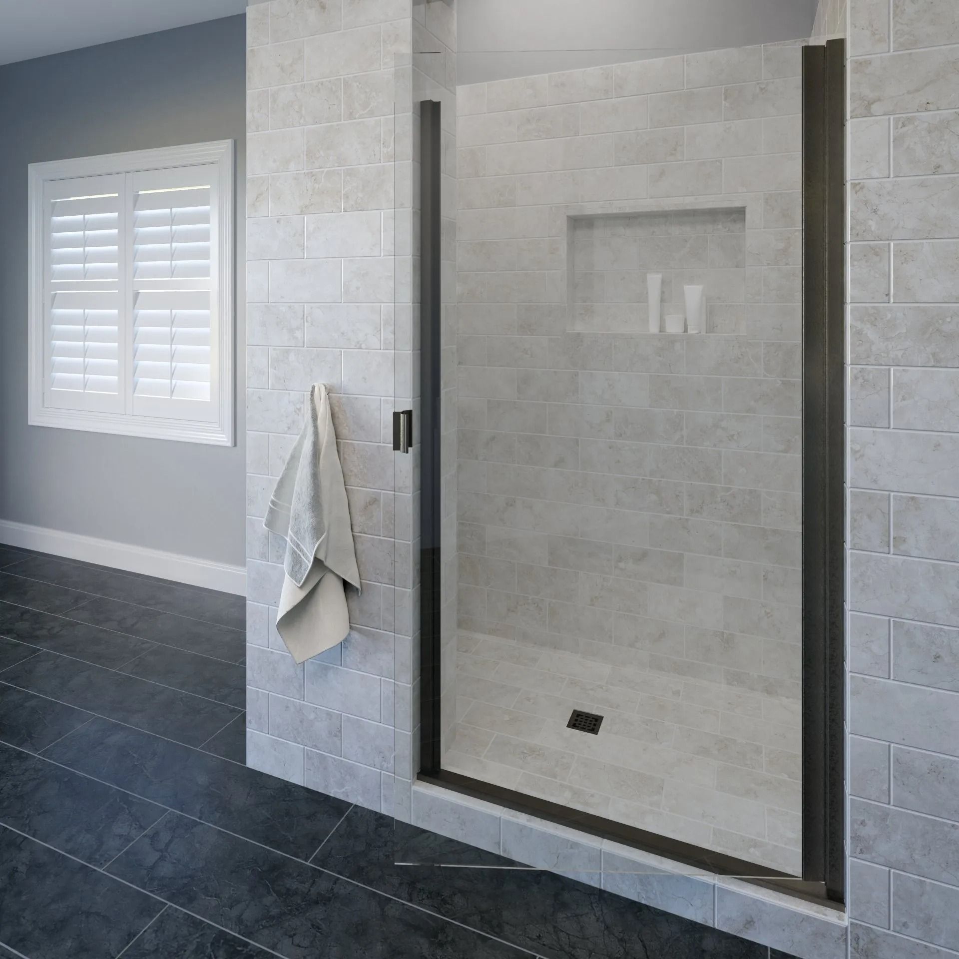 A glass shower door with a dark frame, installed in a tiled alcove with a built-in recessed shelf and a grey tiled floor.
