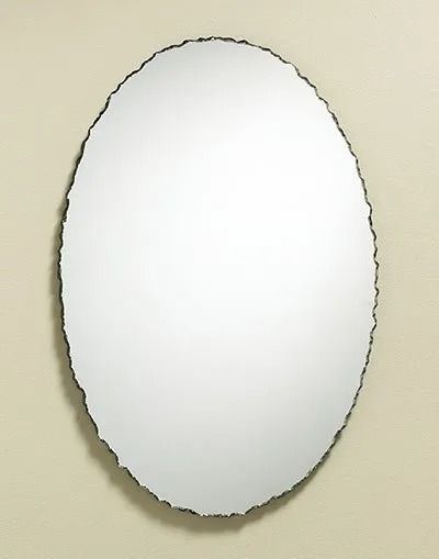 An oval wall mirror with a textured, dark, organic edge hanging on a light beige wall.