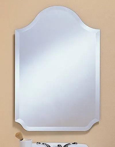 A decorative wall mirror with a scalloped top edge, hung above a bathroom sink fixture.