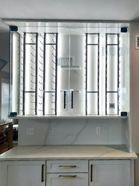 A modern wet bar featuring a white marble countertop and backsplash beneath custom backlit glass wine storage shelves.