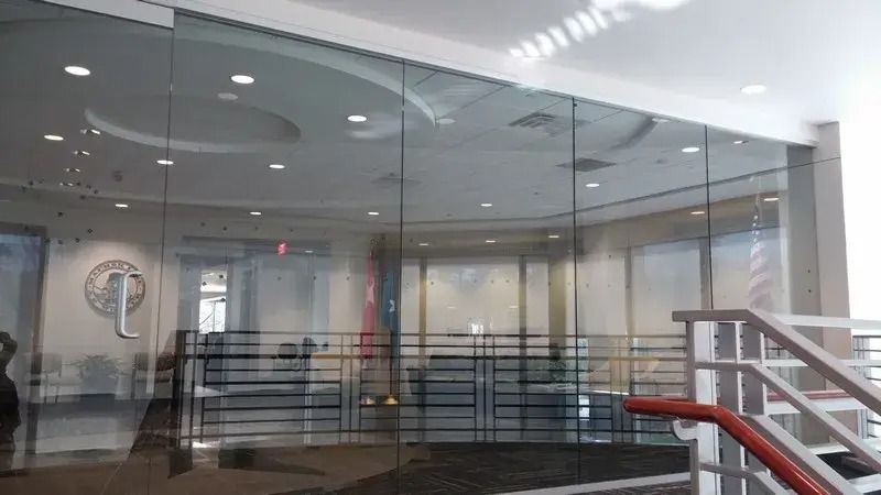A glass wall with stairs leading up to it in a building.