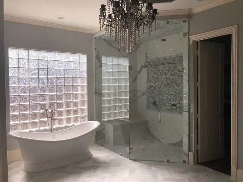 A bathroom with a bathtub , shower , and chandelier.