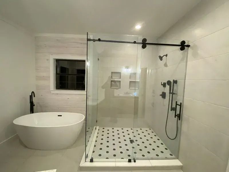 A bathroom with a bathtub and a shower with a sliding glass door.
