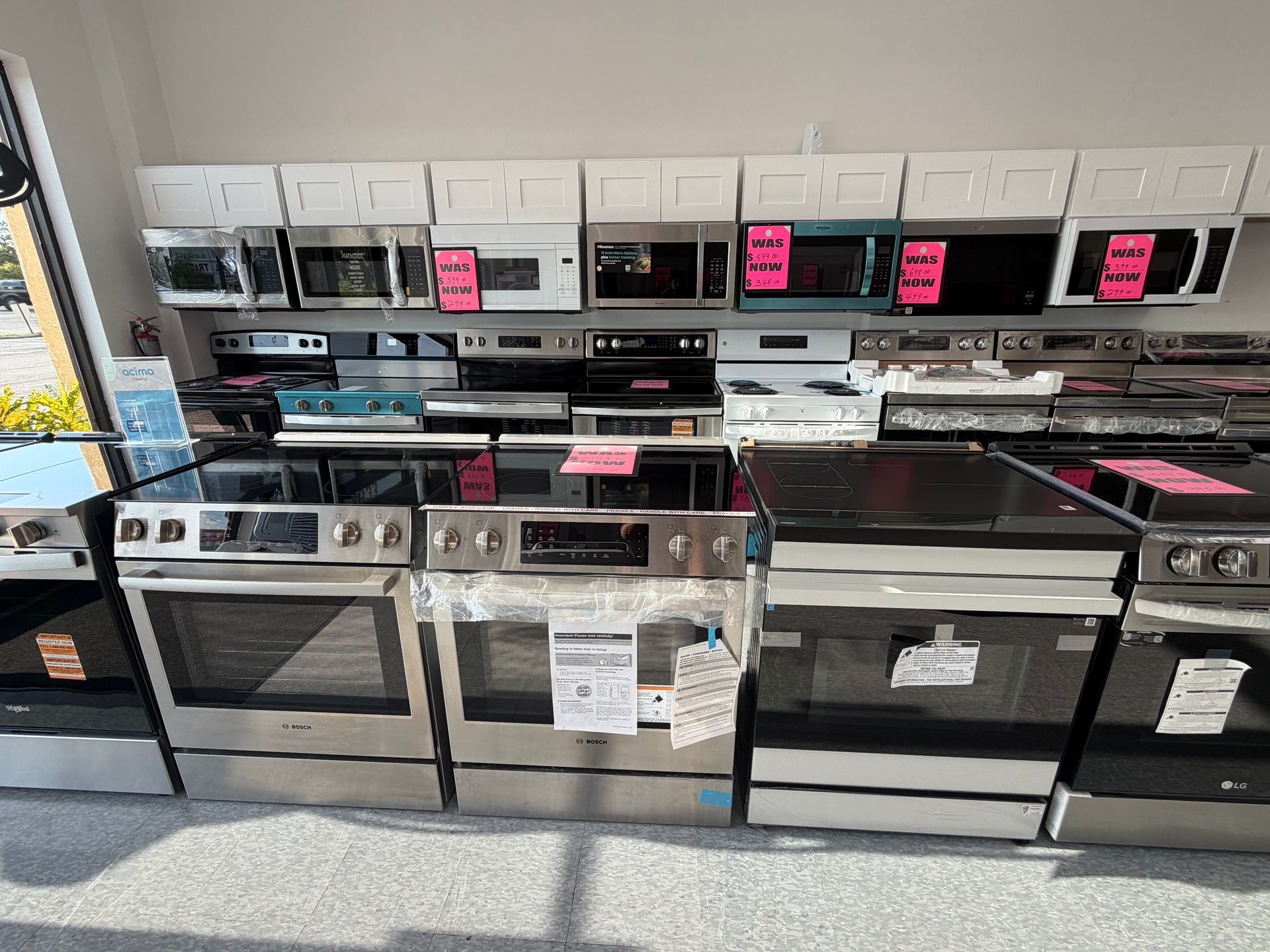 Row of stainless steel and black kitchen ranges and ovens on display in a store showroom