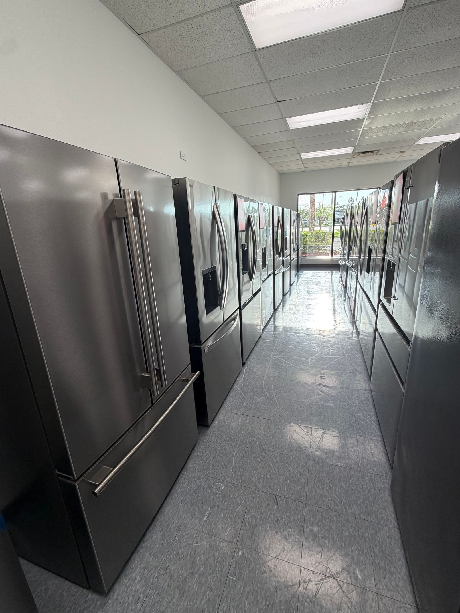 Commercial kitchen corridor lined with stainless steel appliances and bright overhead lights