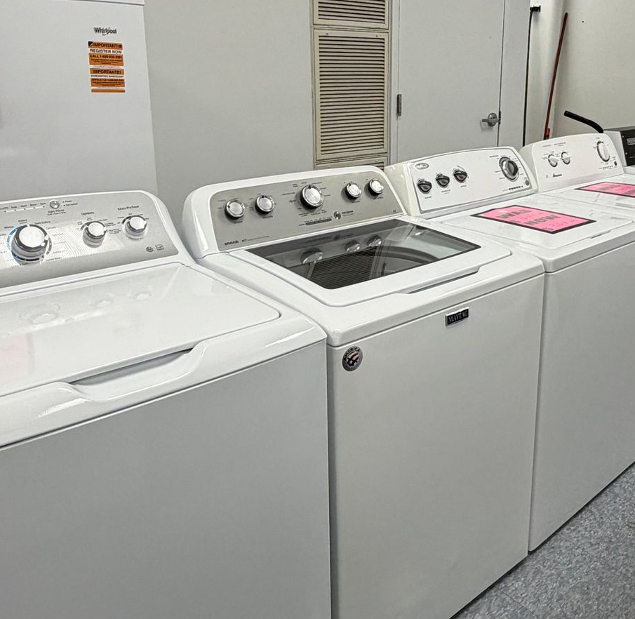 Laundry room with white top-loading washers and dryers lined up along a wall