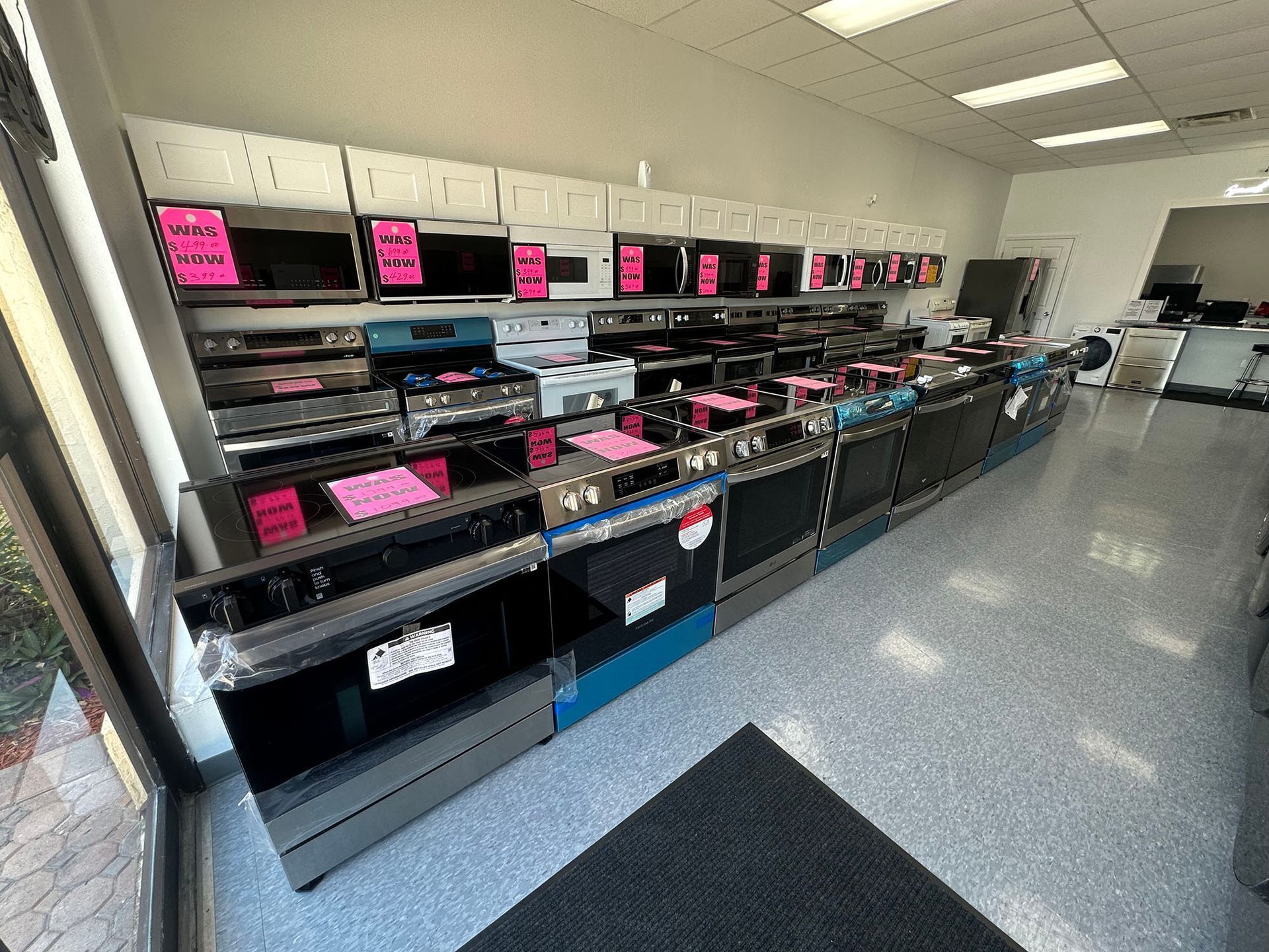 Store interior with empty glass display cases and pink signs along the wall
