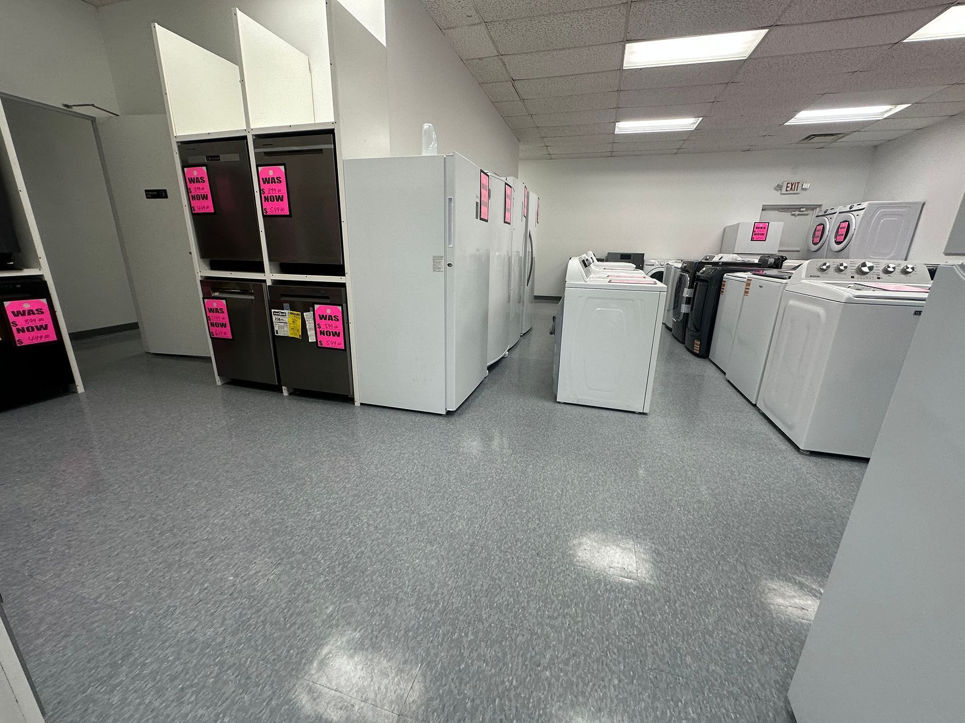 Laundry room with rows of washers, dryers, and folding stations under bright ceiling lights