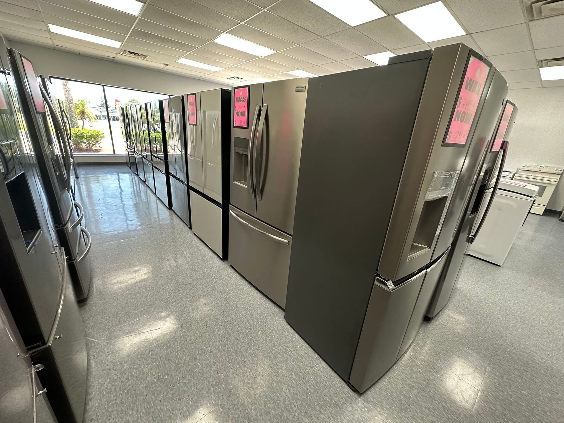 Bright retail aisle with stainless steel refrigerators and a polished floor under fluorescent lights