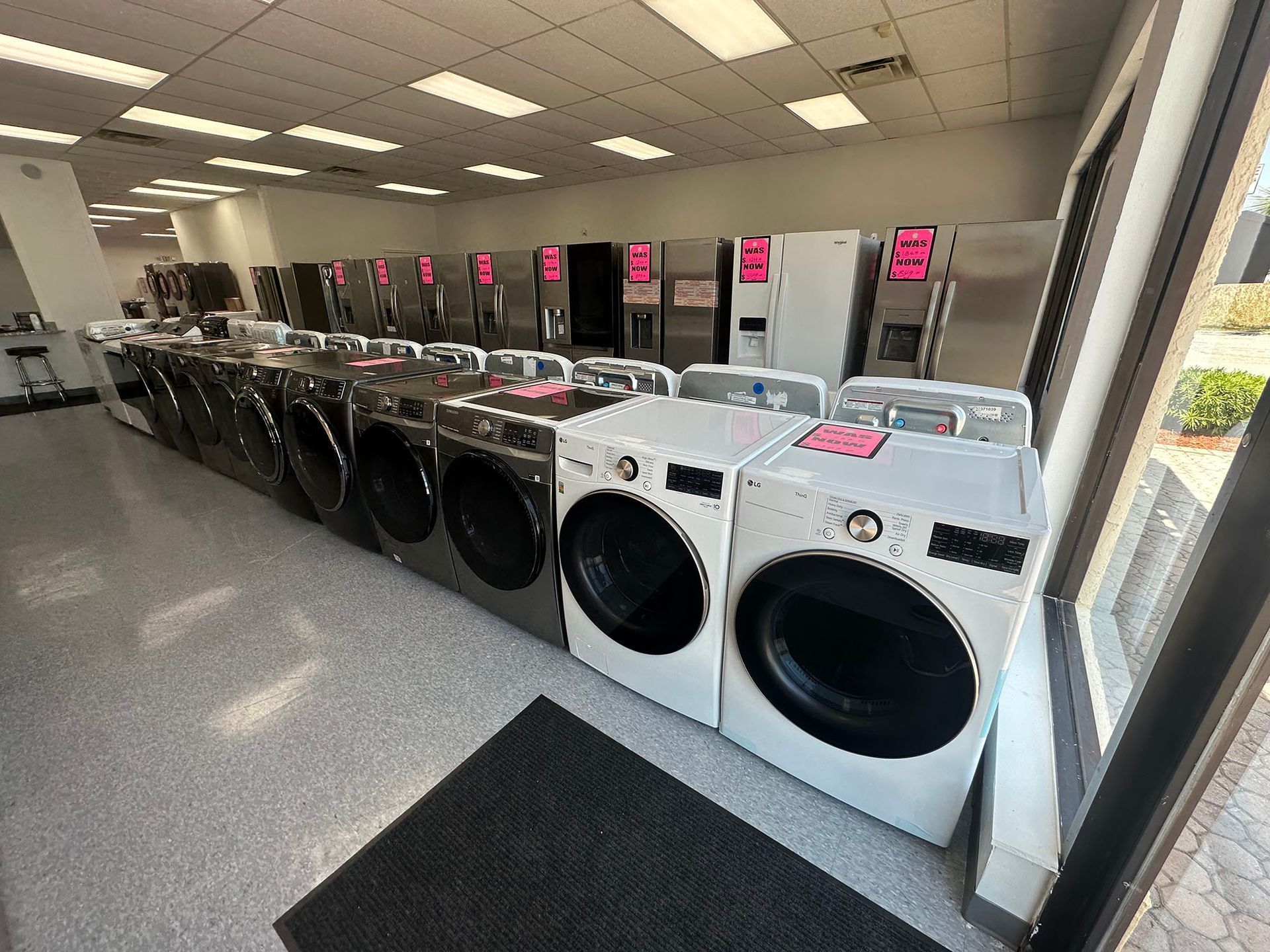 Laundry store with rows of front-loading washers and dryers under bright ceiling lights