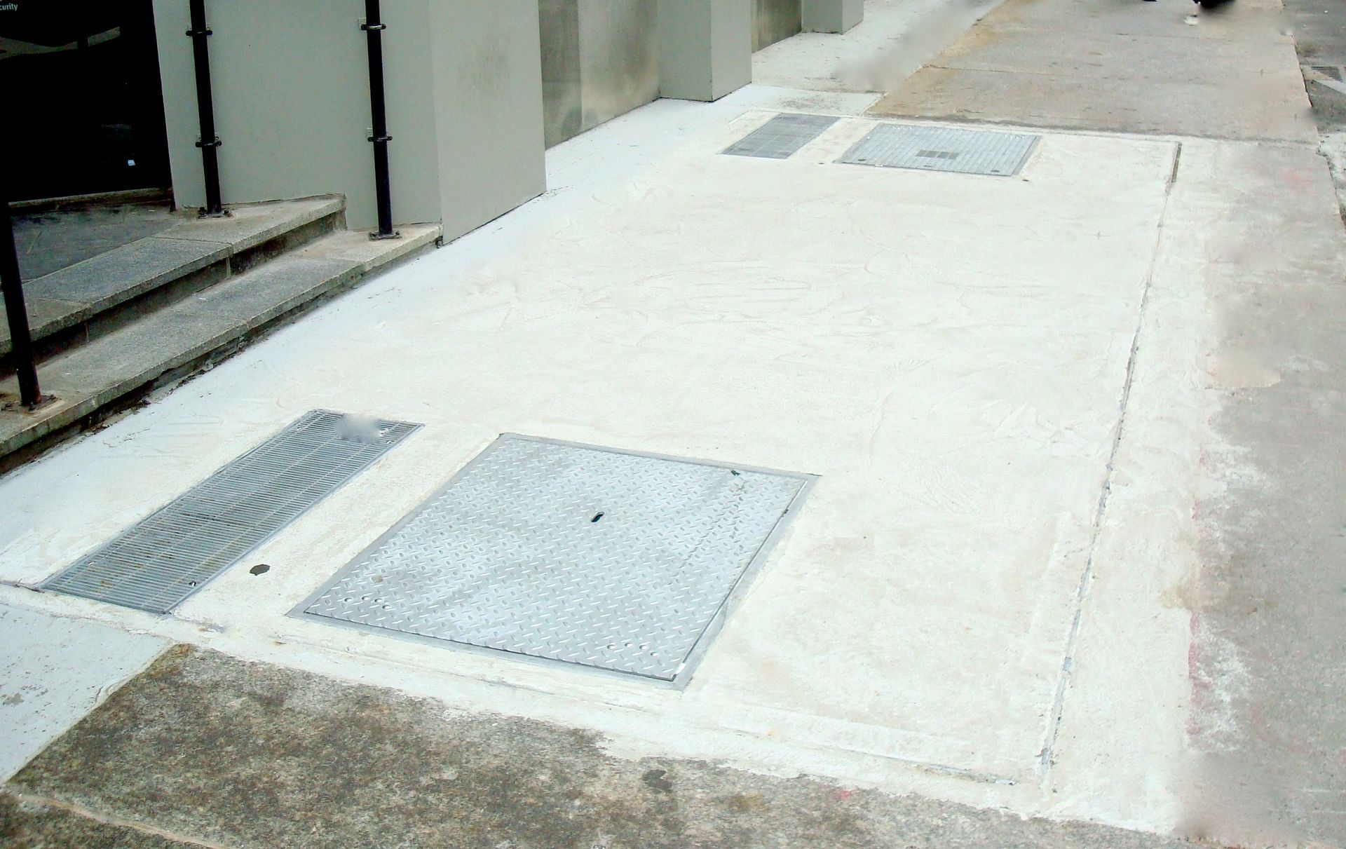 A manhole cover is sitting on a sidewalk next to a building.