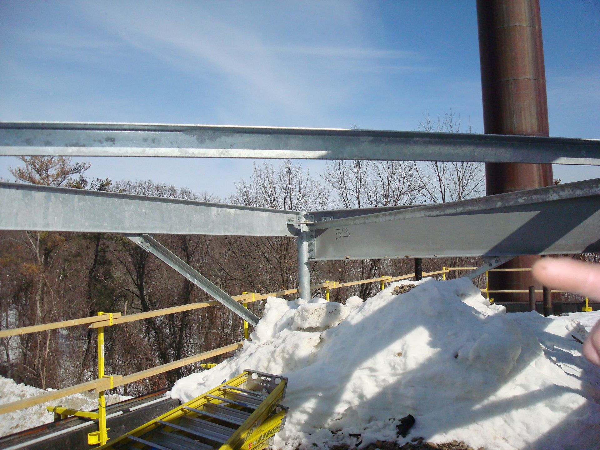 A person is pointing at a metal structure in the snow