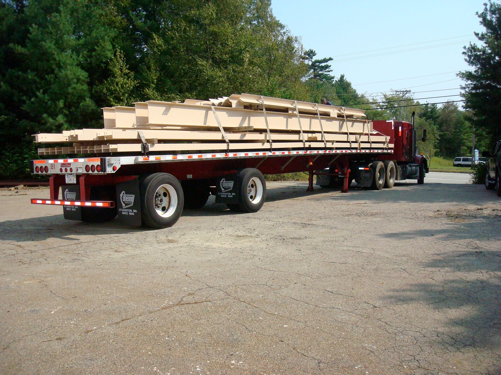A red semi truck is carrying a large load of wood
