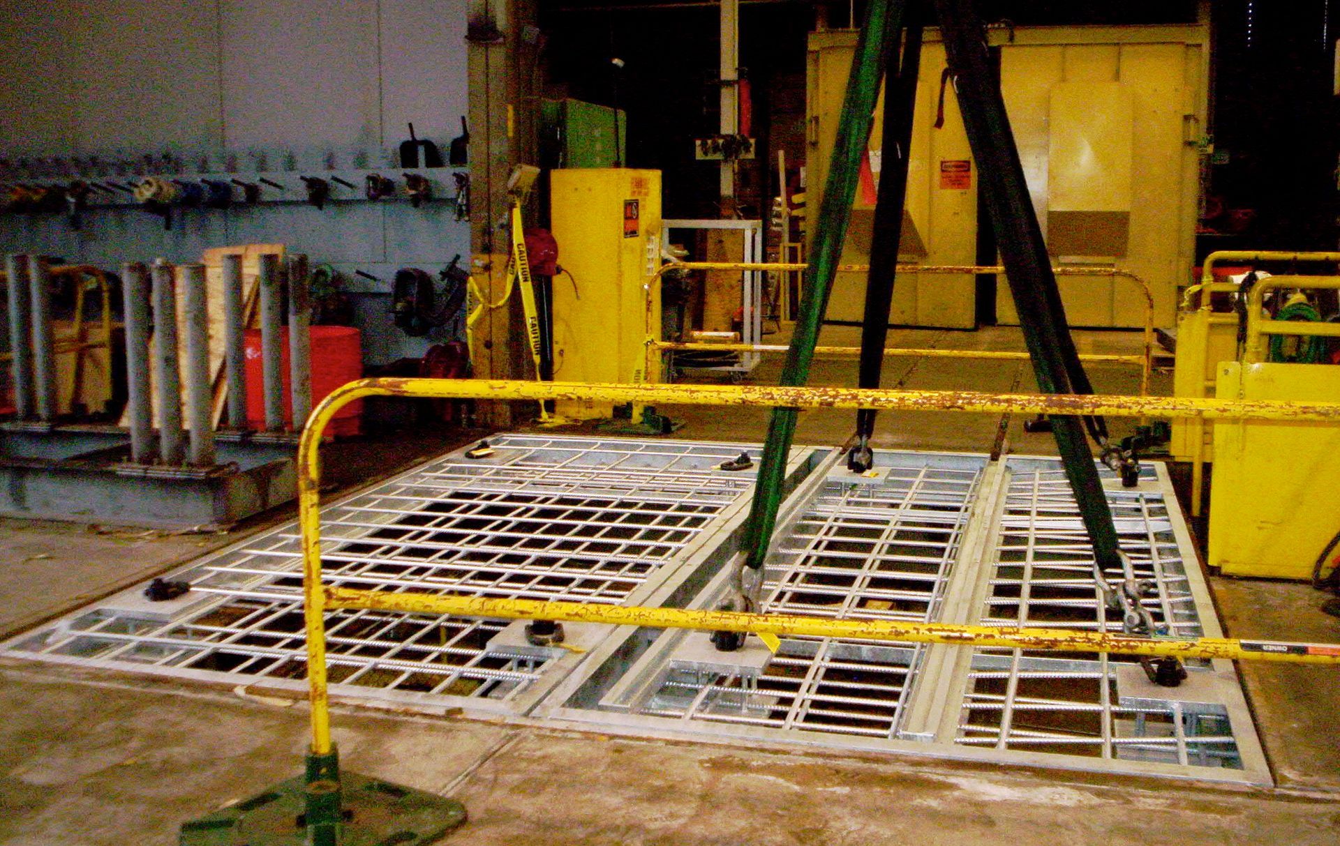 A yellow fence surrounds a large metal grid in a factory