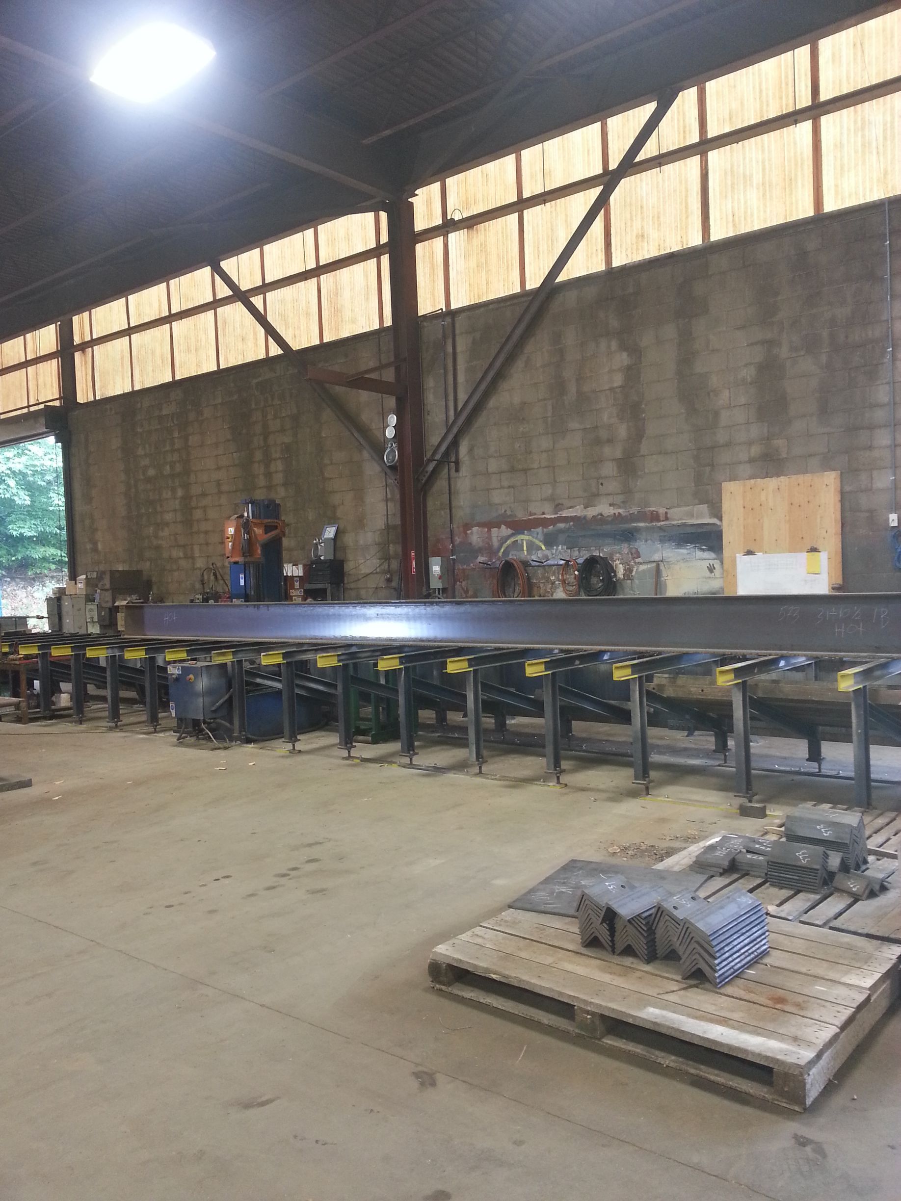 A large metal beam is sitting on top of a wooden pallet in a factory.