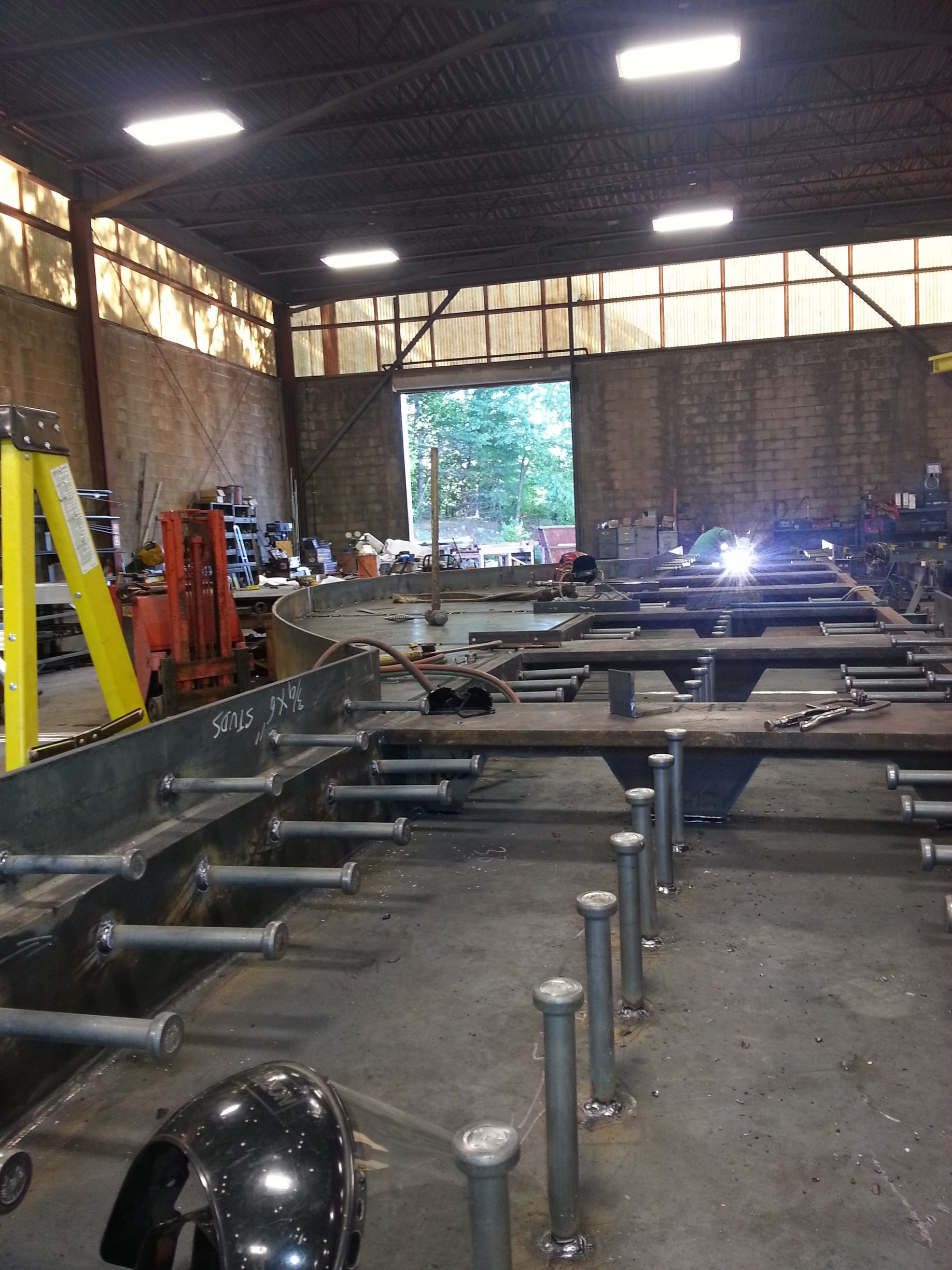 A warehouse filled with lots of metal pieces and a yellow ladder.