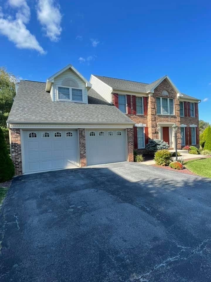 Suburban brick-and-siding house with a two-car garage and driveway under a blue sky.
