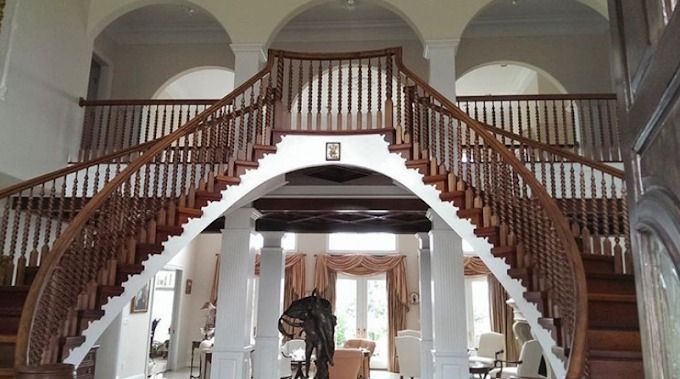 Grand double staircase in a bright foyer with arched openings and a chandelier above