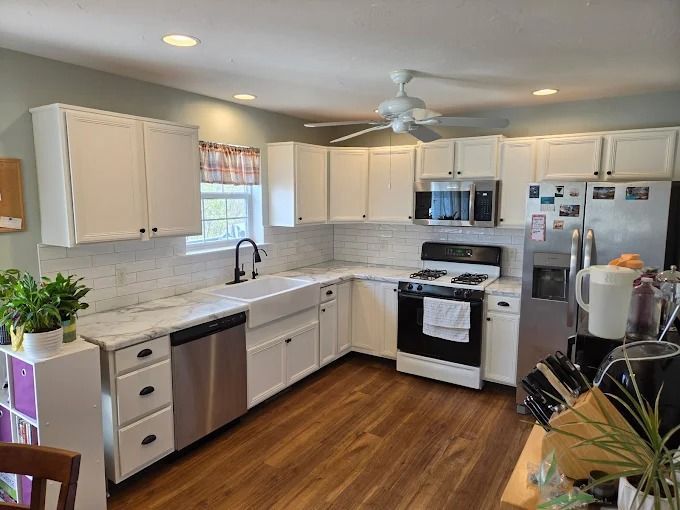 Bright modern kitchen with white cabinets, stainless appliances, and wood floors