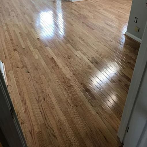 Shiny hardwood floor in an empty room, viewed from a doorway.