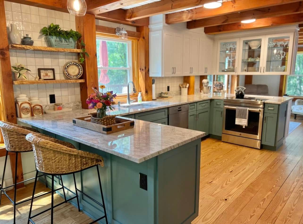 Bright rustic kitchen with teal island, wood beams, white cabinets, and stainless-steel oven