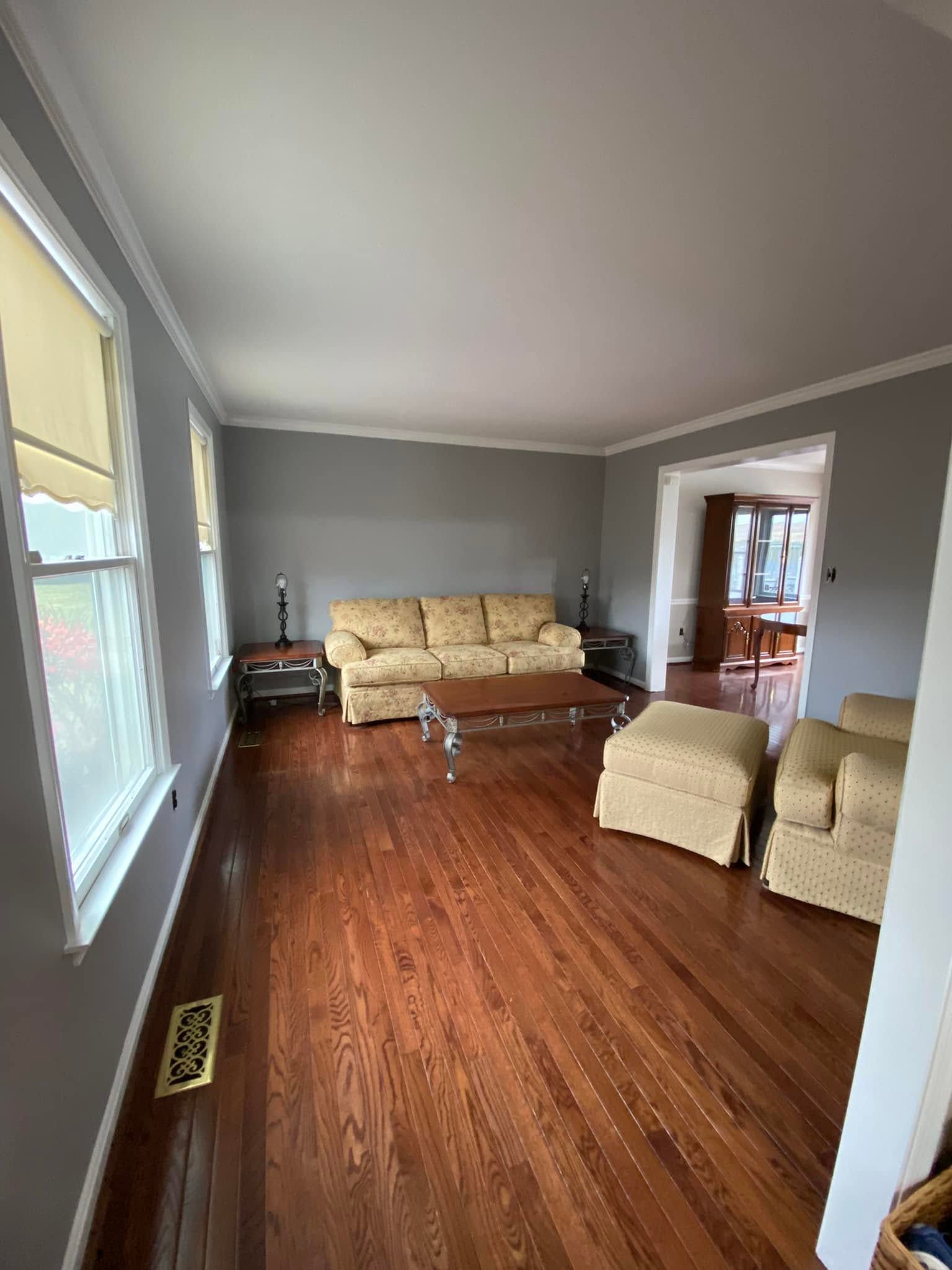 Living room with beige sofas, wood floor, and large windows on the left.