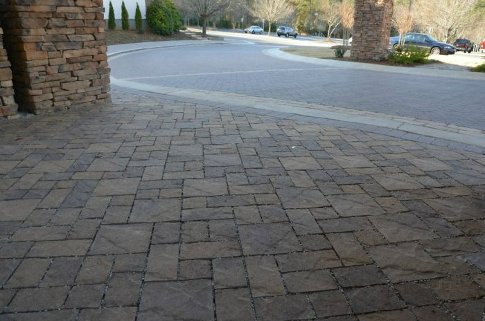 a brick driveway with a stone wall in the background