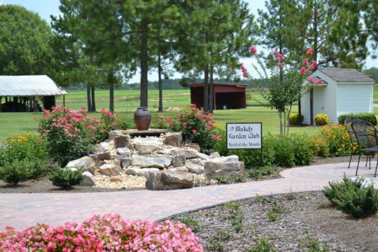 a garden with a waterfall and a sign that says welcome garden club