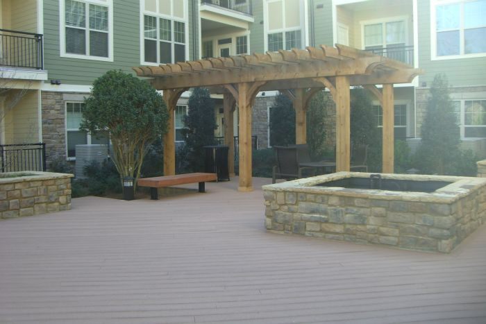 a wooden pergola with a fire pit in front of a building