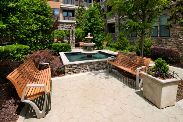 a patio with two wooden benches and a fountain in the background