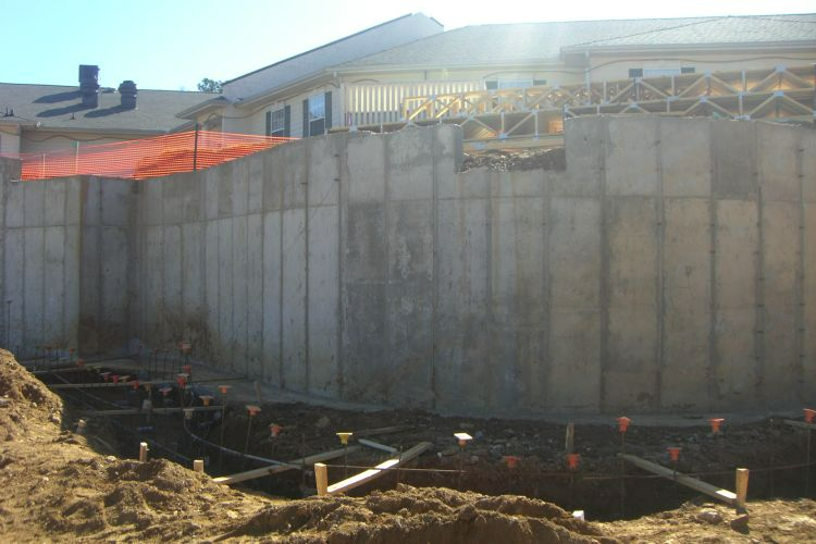 a large concrete wall with a hole in the ground in front of it