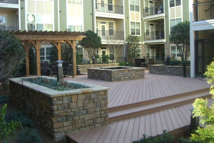 a deck with a pergola and a fire pit in front of a building