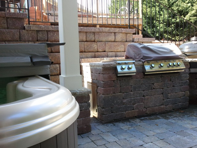 a hot tub is next to a grill on a patio