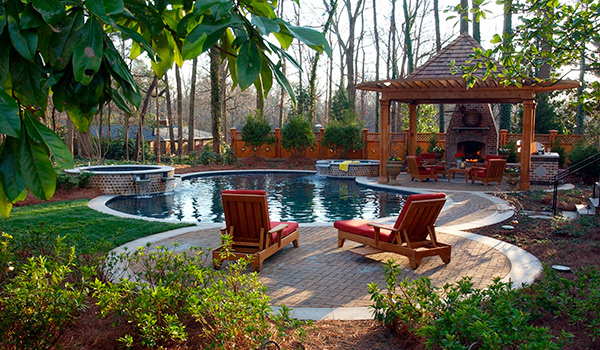a backyard with a swimming pool , chairs , a gazebo and a fireplace .