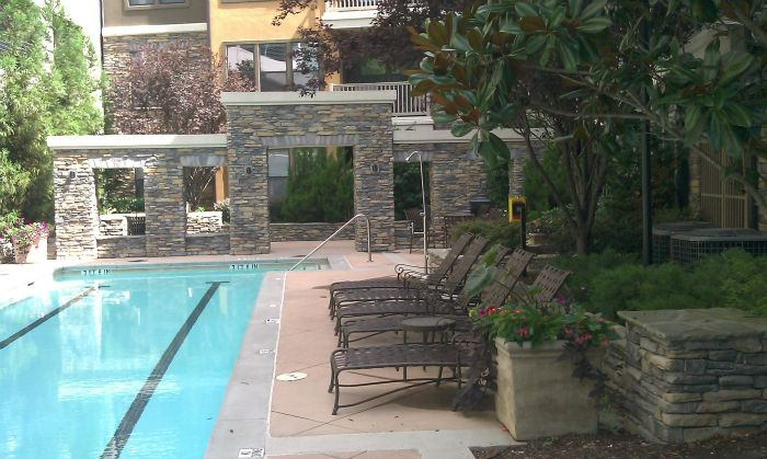 a large swimming pool surrounded by chairs and a building