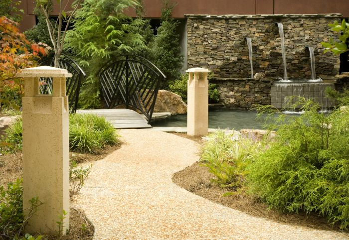 a walkway with a bridge and a waterfall in the background