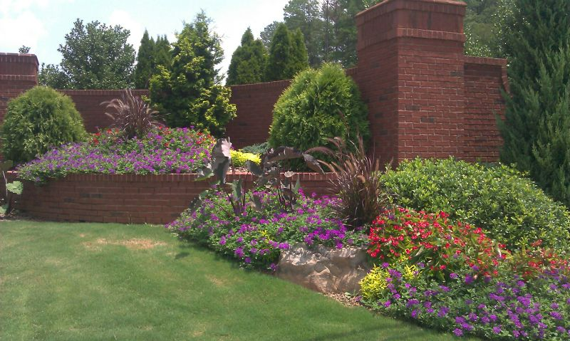 a brick wall with a lot of flowers in front of it.