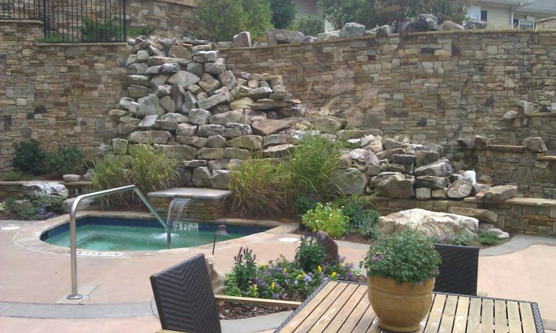 a patio with a table and chairs next to a pool and a waterfall .