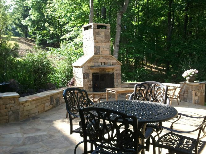 a patio with a table and chairs and a fireplace