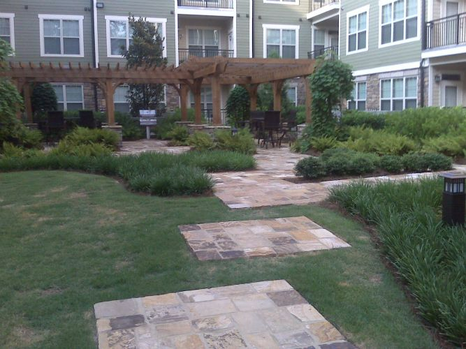 a large apartment building with a lush green lawn and a pergola .