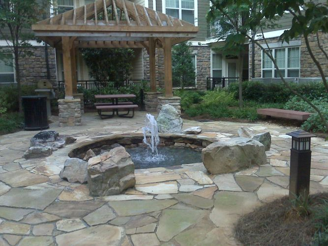 a fountain is in the middle of a stone patio